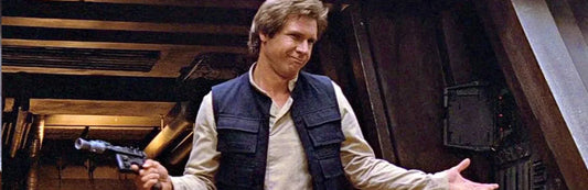 A screenshot of Han Solo from the Return of the Jedi film. He stands holding his arms out on either side of him and has a cocky smile.